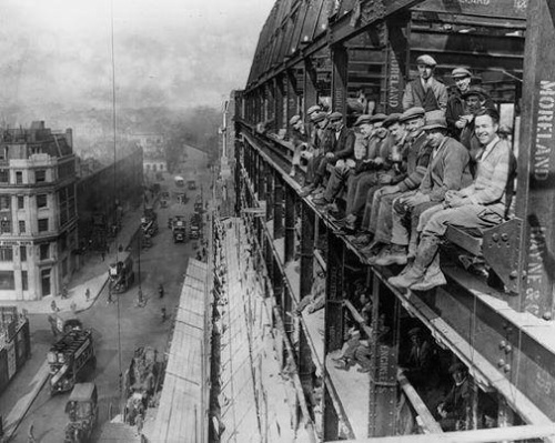 Construction workers on lunch break on the edges of the building they're working on, London, 1929